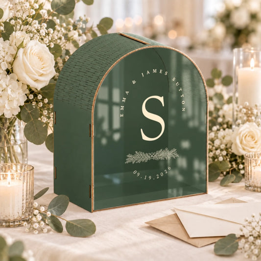 Personalized green monogram wedding card box with botanical initial, couple names, and wedding date displayed at an elegant reception